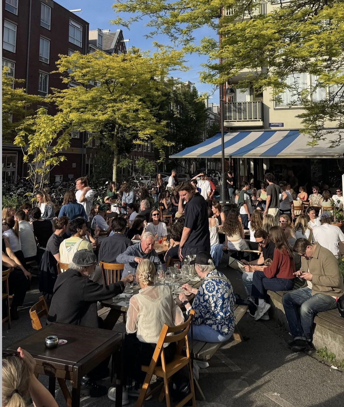 Een druk terras van Café Publiek op het Dapperplein in de avondzon