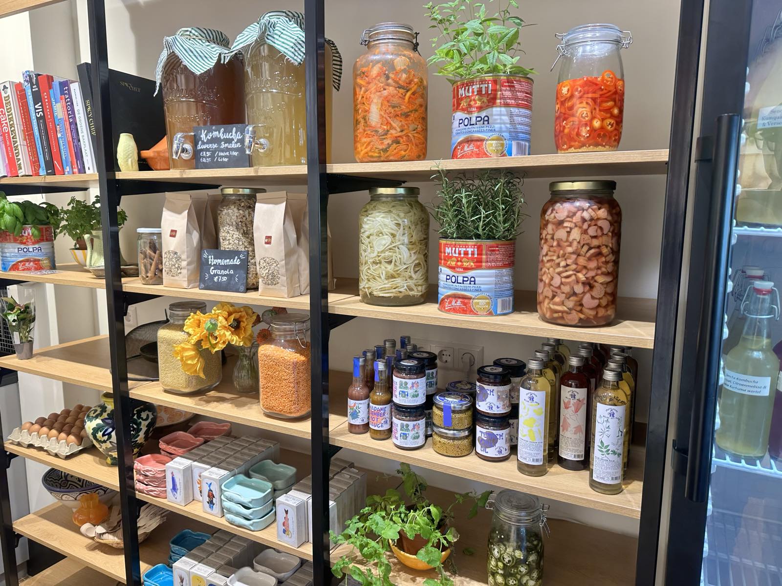 De kleurrijke stelling met zelfgemaakte kombucha, kimchi, jams, oliën en andere delicatessen