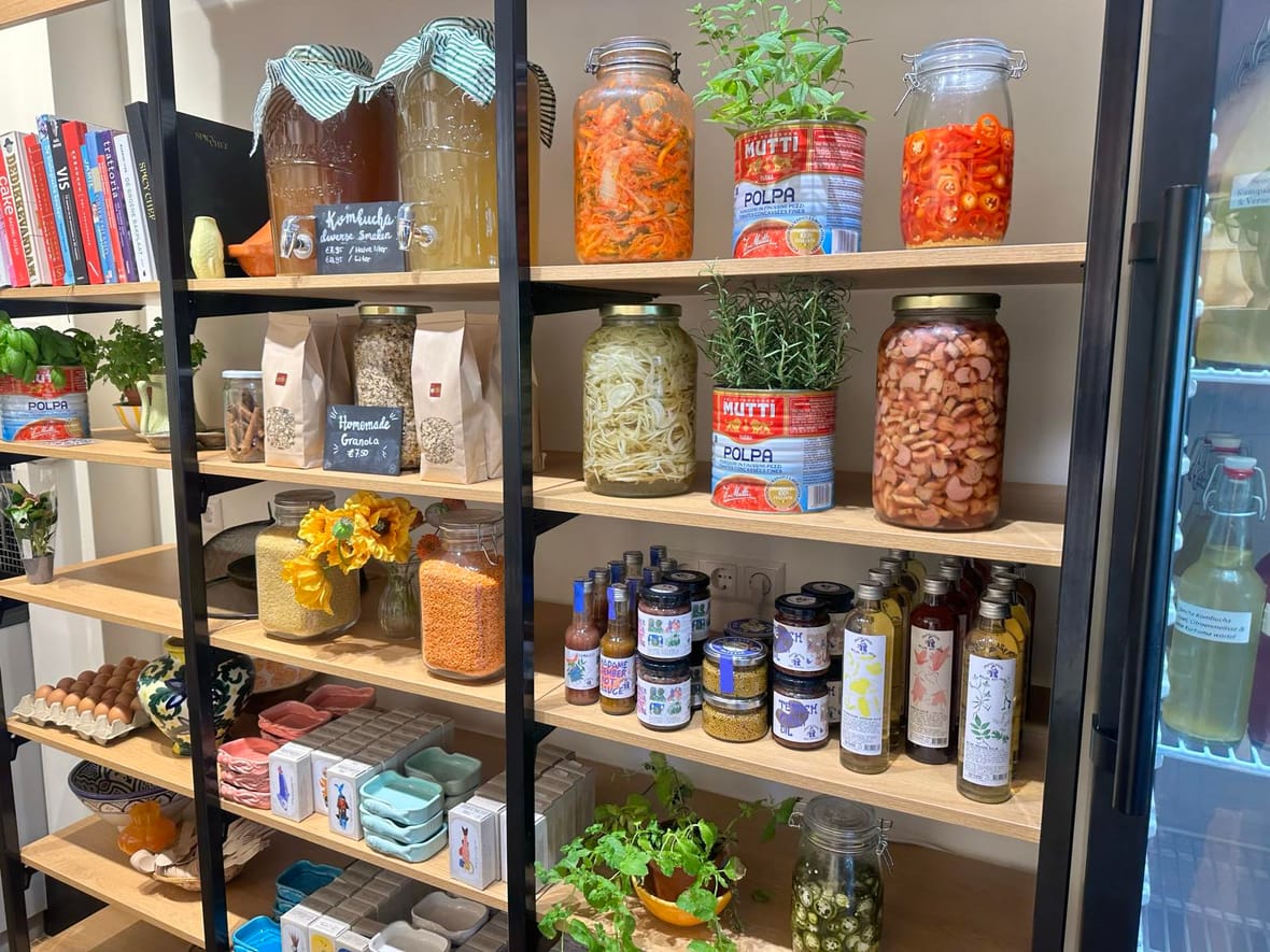 De kleurrijke stelling met zelfgemaakte kombucha, kimchi, jams, oliën en andere delicatessen