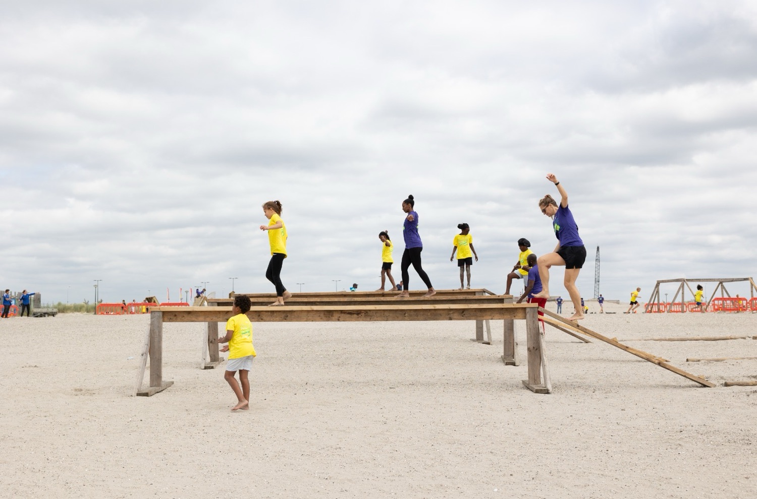 Deelnemers lopen over een balk tijdens het parcours van de Obstacle Run
