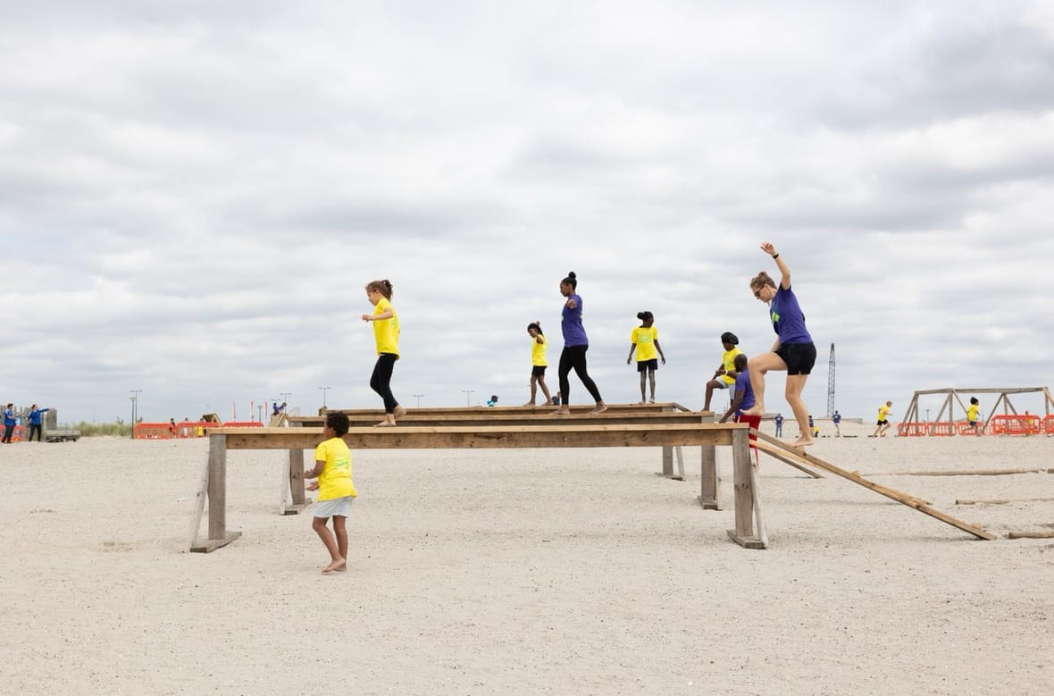 Deelnemers lopen over een balk tijdens het parcours van de Obstacle Run