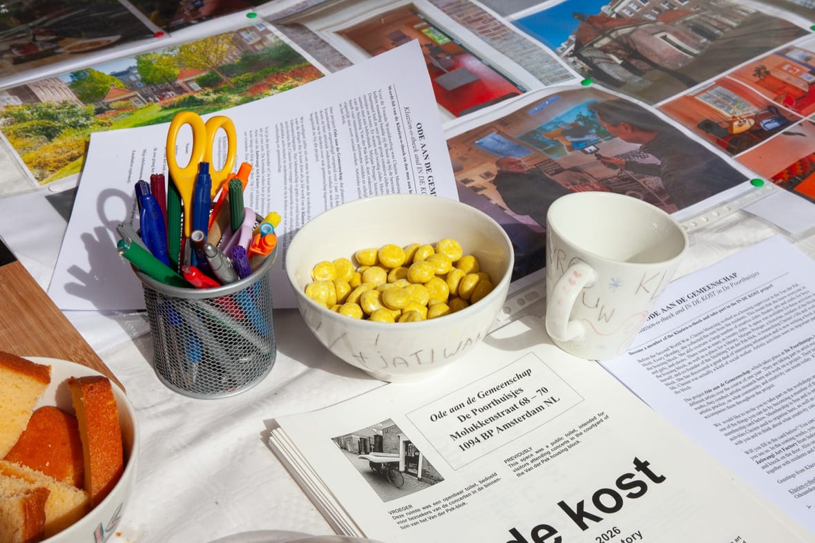 Tafel met materiaal voor IN DE KOST: flyers, potloden en informatie over Ode aan de Gemeenschap