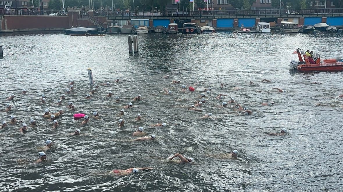 Zwemmers van LoveSwim in de Amstel, met de reddingsboot van de veiligheidsbrigade op de uitkijk