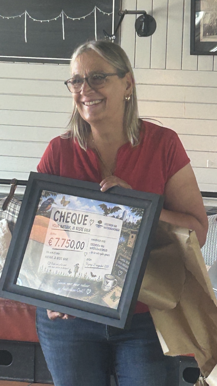Els, vrijwilliger van Natuur, je beste buur, houdt trots de ingelijste cheque vast