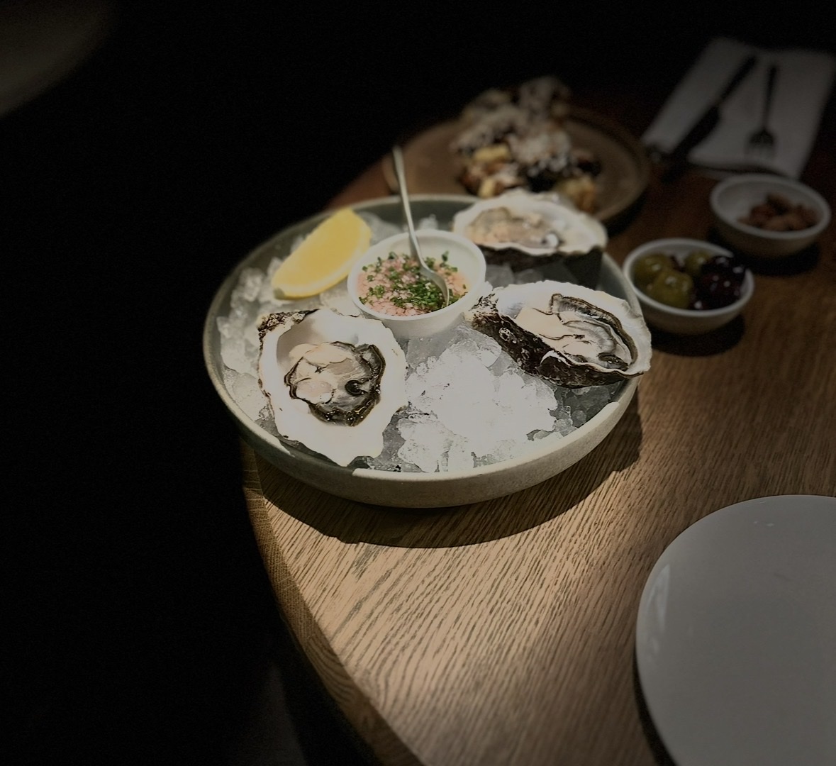 Bord met oesters op ijs, met mignonette en wat bijgerechten, in een restaurant