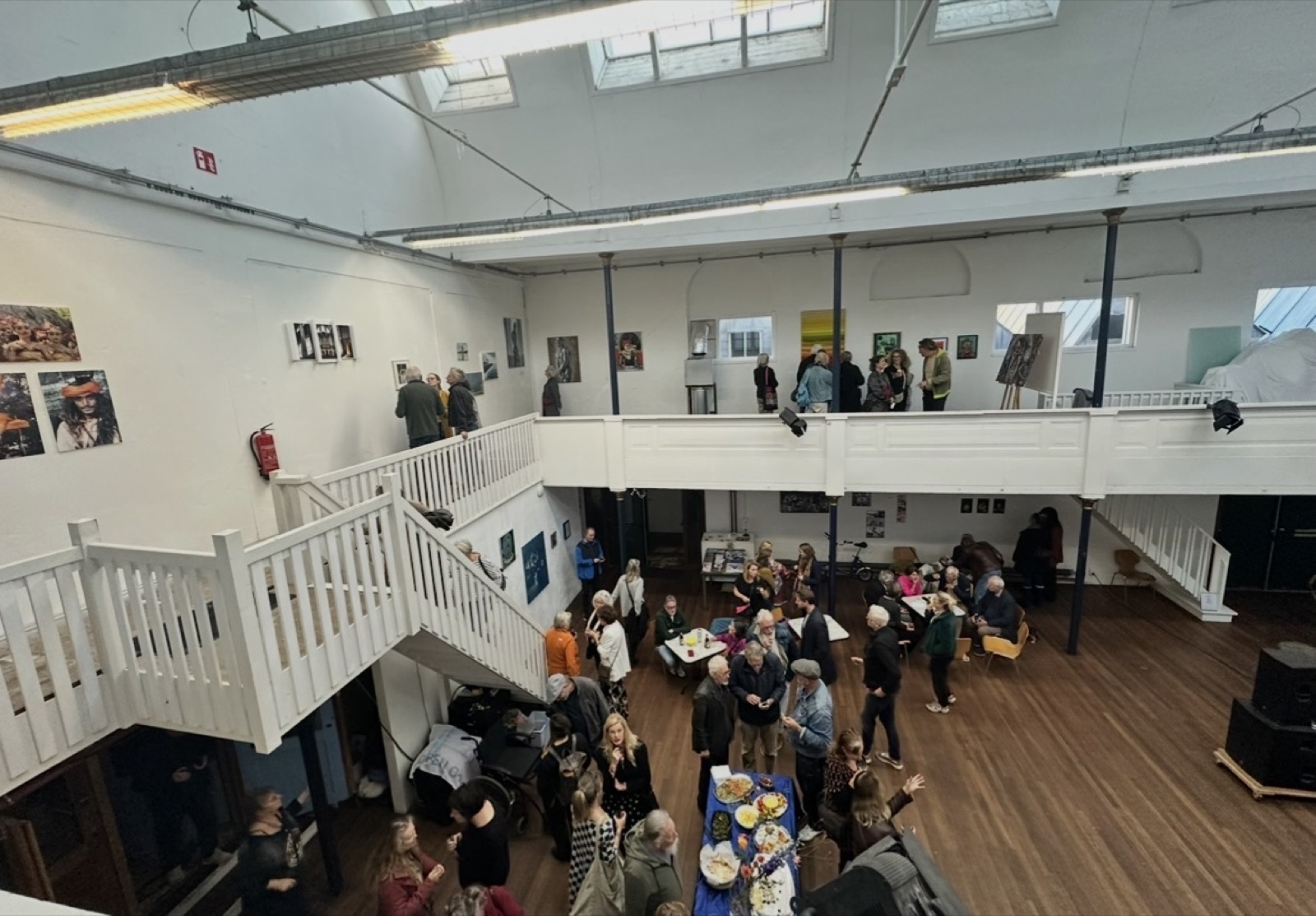 Bezoekers in een ruime expositiehal met kunstwerken aan de muren en een bovengalerij, tijdens een eerdere editie van Oosterkunst