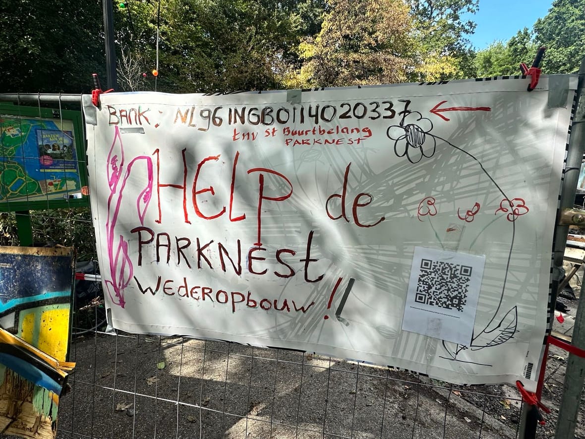 Spandoek bij Parknest: ‘HELP de Parknest wederopbouw!!’, met bankgegevens en een QR-code