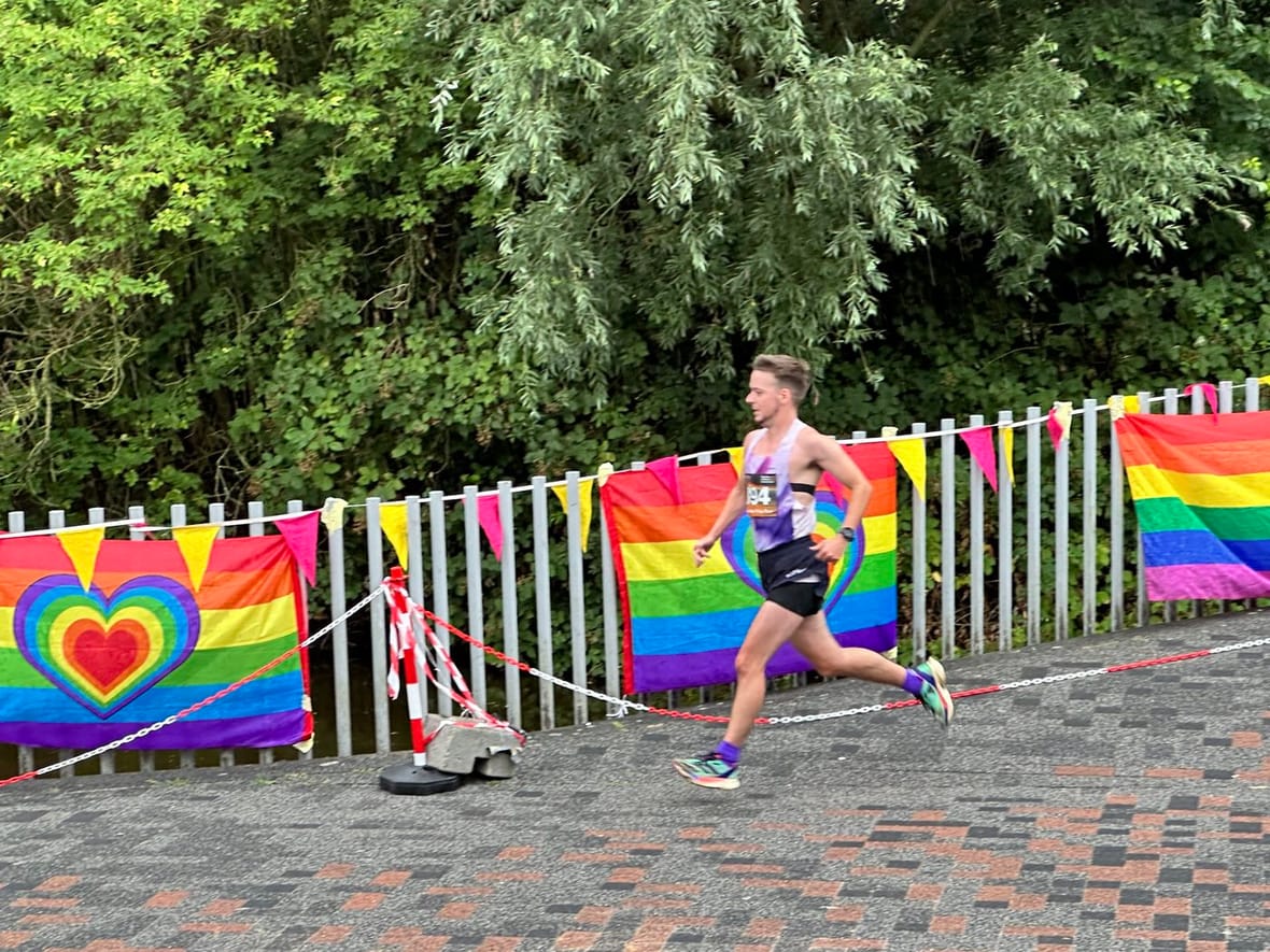 Hardloper tijdens de Amsterdam Pride Run, tussen regenboogvlaggen langs de route