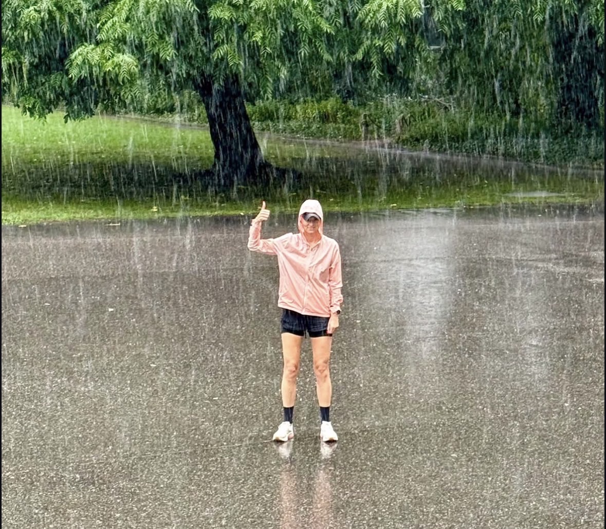 Een deelnemer steekt tijdens de social run in de stromende regen haar duim op