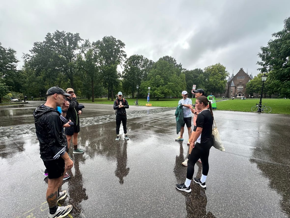 De deelnemers verzamelen zich voor de warming-up op het natte asfalt in het Oosterpark
