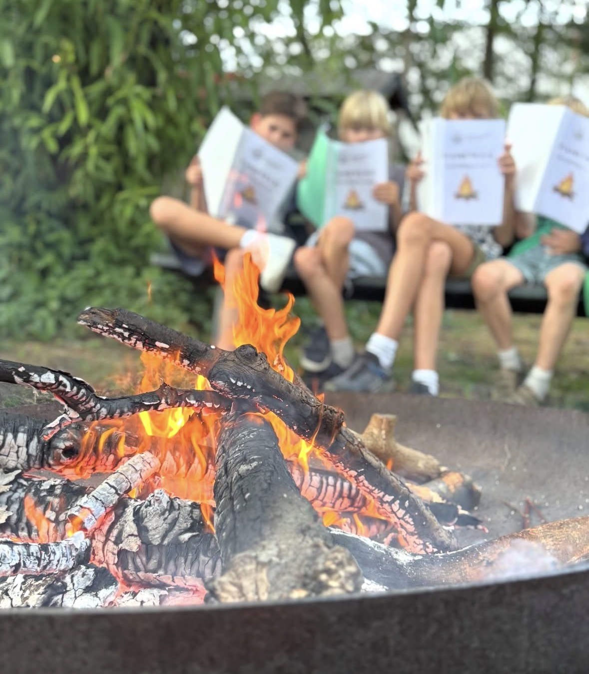 Kinderen zitten bij het kampvuur tijdens een activiteit van Scouting Oost 1