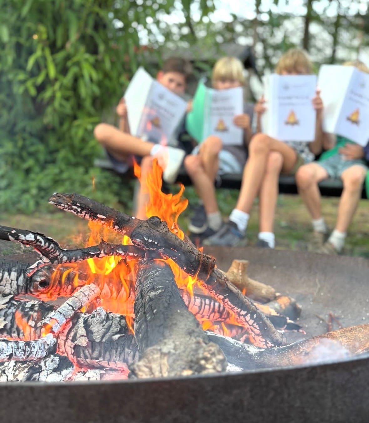 Kinderen zitten bij het kampvuur tijdens een activiteit van Scouting Oost 1