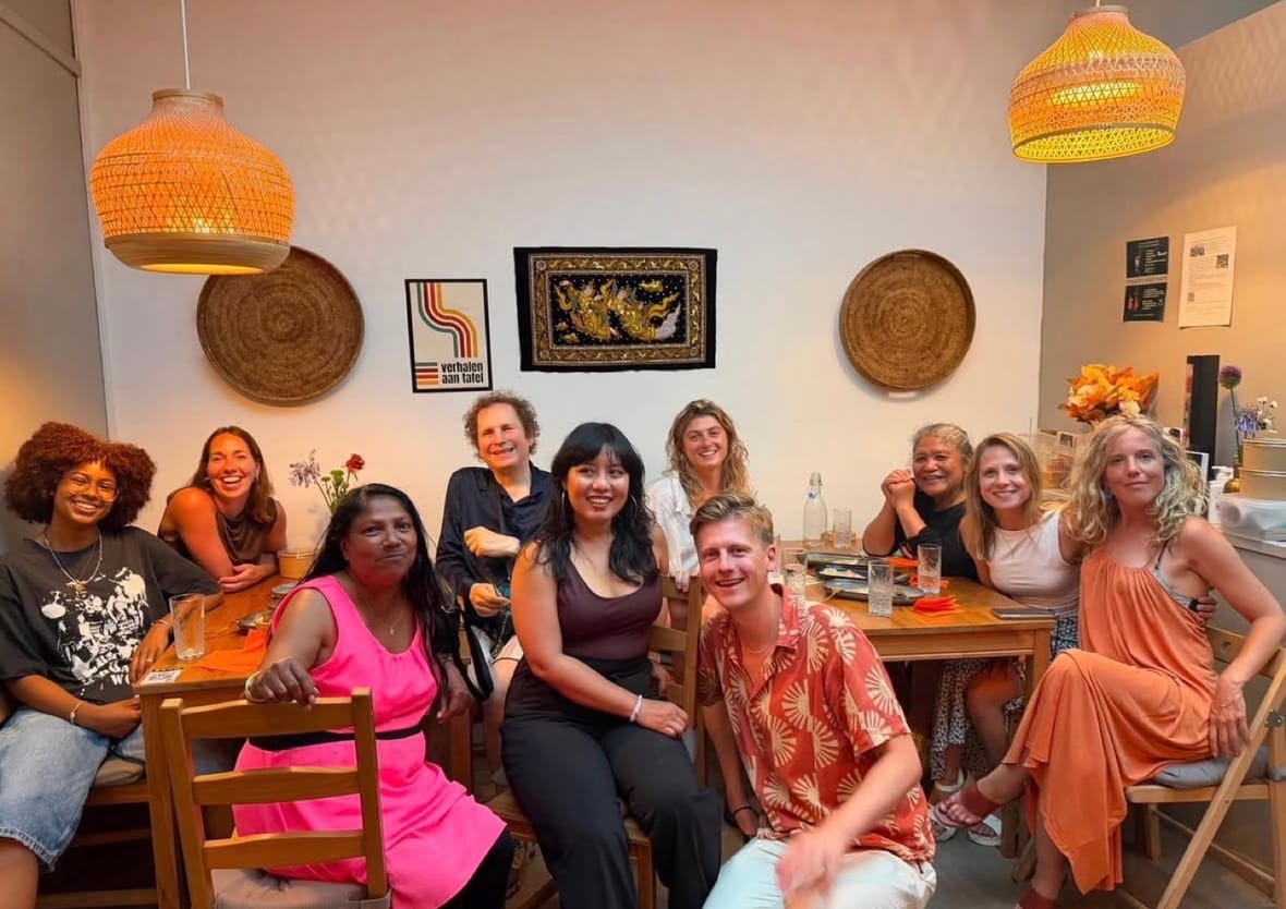 Deelnemers van Verhalen aan Tafel zitten lachend aan een lange tafel bij Yangon Delight